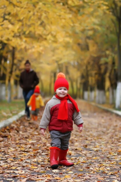 Il bambino nel parco autunnale cammina con la famiglia e sorride