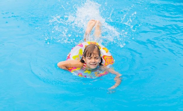 Il bambino nuota in piscina in estate.