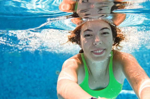 Il bambino nuota sott'acqua in piscina una ragazza adolescente attiva e felice si tuffa e si diverte sott'acqua