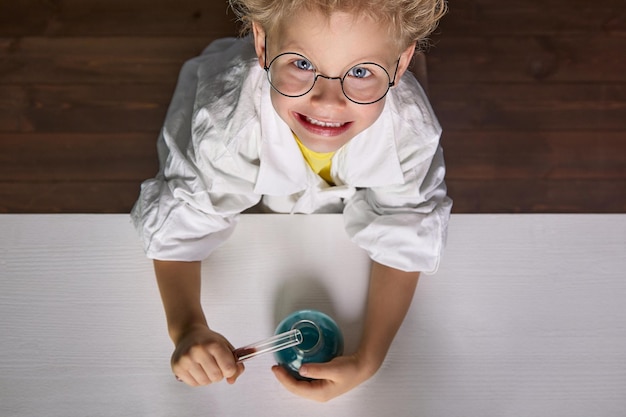 Il bambino pone l'assistente di laboratorio in classe di chimica con reagenti chimici reali