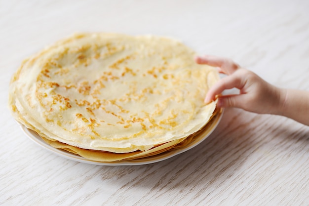 Il bambino prende un pancake da un piatto con i pancake