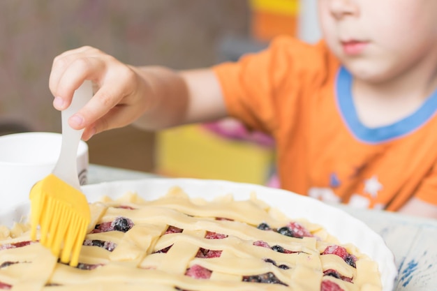 Il bambino prepara una torta Il bambino spalma la parte superiore della torta