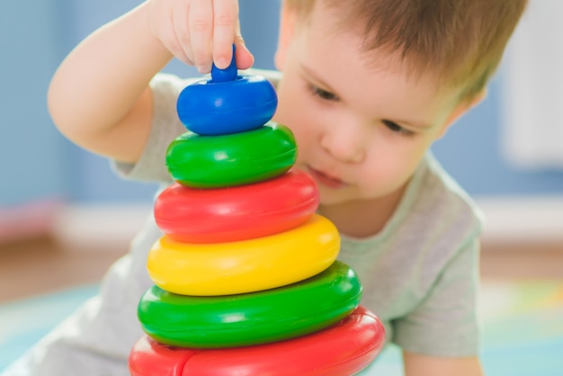 Il bambino raccoglie un piraimda seduto su un pavimento