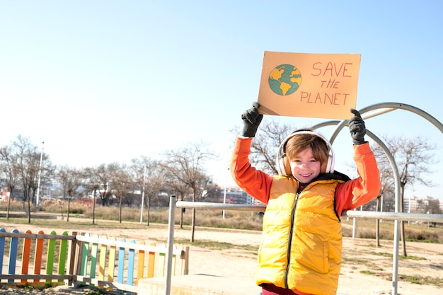 Il bambino regge il cartello con le braccia alzate per salvare il pianeta nel parco