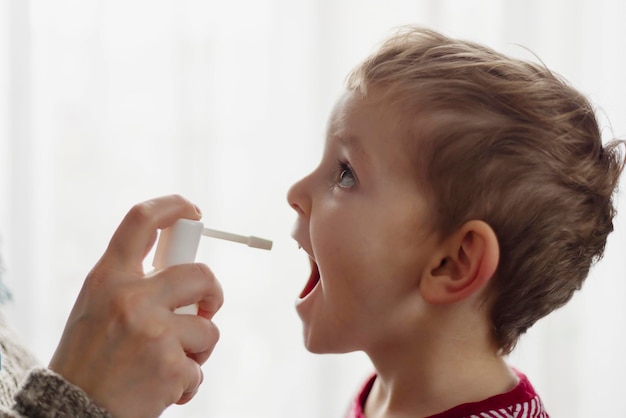 Il bambino riceve farmaci attraverso uno spray per la bocca per un mal di gola