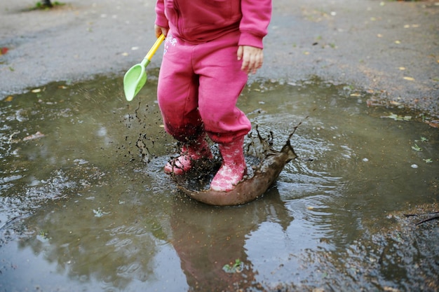 Il bambino salta in una pozzanghera sporca