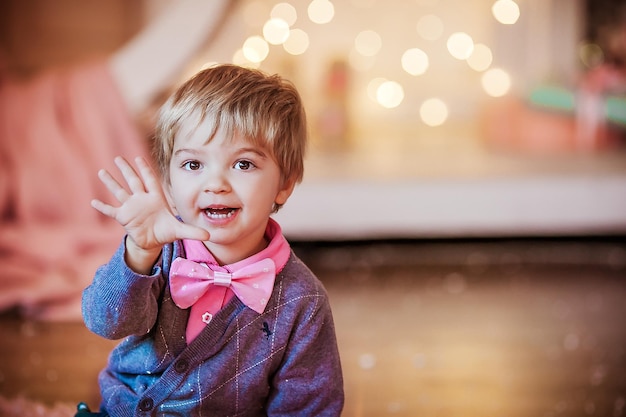 Il bambino si avvicina alla vigilia di capodanno con un grande papillon rosa