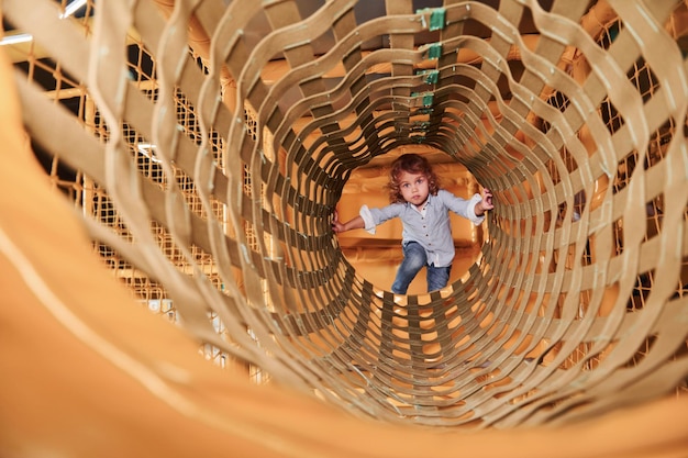 Il bambino si diverte nella sala giochi passando attraverso la gabbia di legno