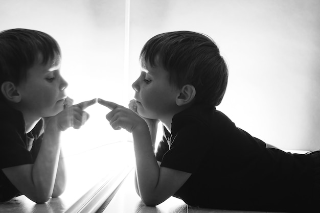 Il bambino si guarda allo specchio in una notte buia