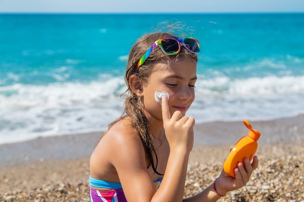 Il bambino si sta mettendo la crema solare sul viso. Messa a fuoco selettiva. Ragazzo.