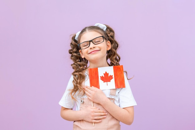 Il bambino sogna di andare in Canada a studiare Una scolaretta tiene la bandiera del Canada e sorride