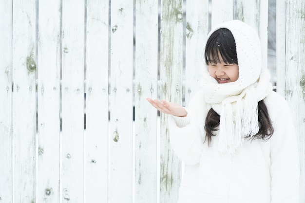 Il bambino sorride mentre tiene con le mani la neve che cade