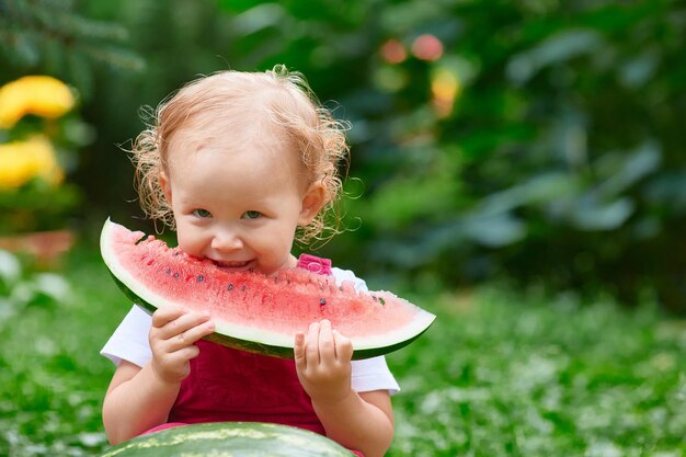 Il bambino sorridente mangia l'anguria fuori in estate. Copia spazio.