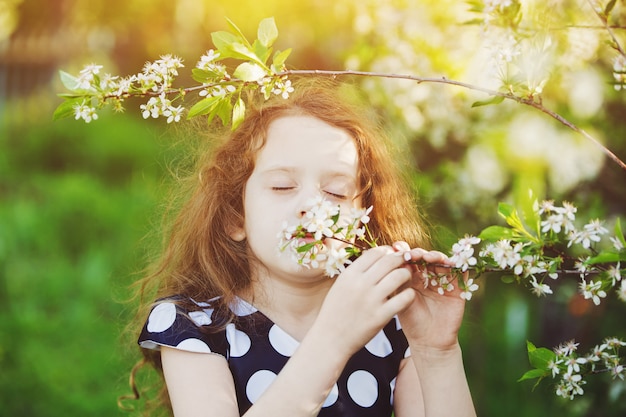 Il bambino sta annusando il ramo di ciliegio in fiore