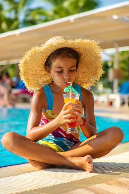 Il bambino sta bevendo un cocktail a bordo piscina. Messa a fuoco selettiva.