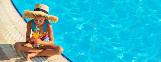 Il bambino sta bevendo un cocktail a bordo piscina. Messa a fuoco selettiva.