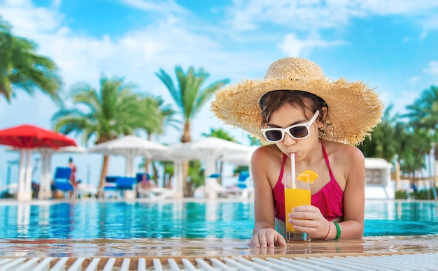 Il bambino sta bevendo un cocktail a bordo piscina