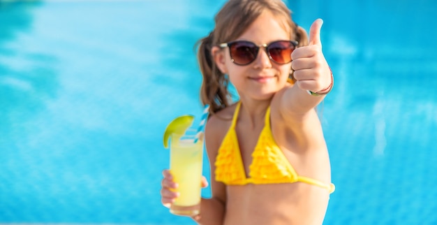 Il bambino sta bevendo un cocktail a bordo piscina