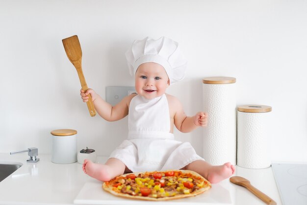 Il bambino sta cucinando la pizza in cucina