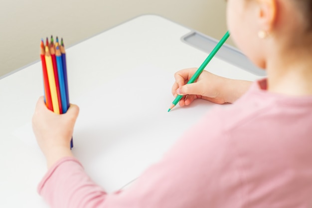 Il bambino sta disegnando con matite colorate.