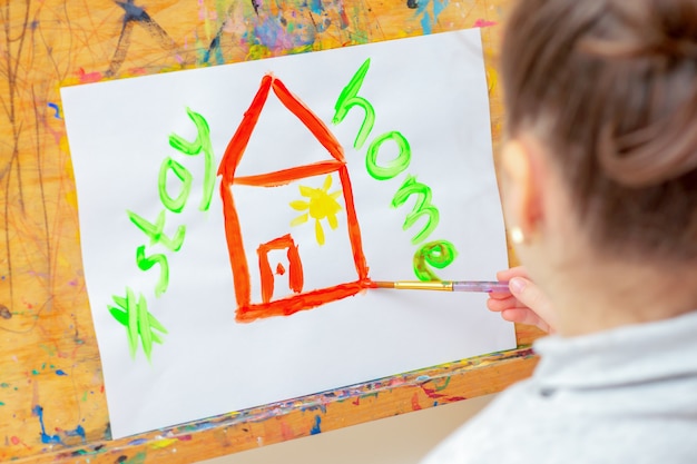 Il bambino sta disegnando la casa rossa con le parole Stay Home