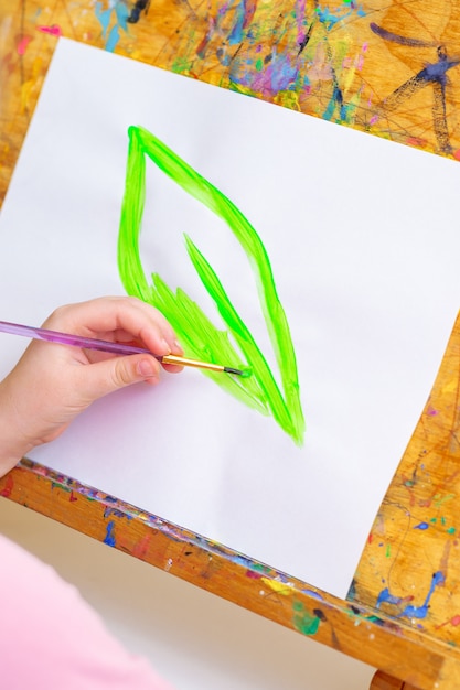 Il bambino sta disegnando la foglia verde su carta.