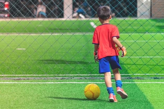 Il bambino sta dribblando Pallone da calcio su un campo