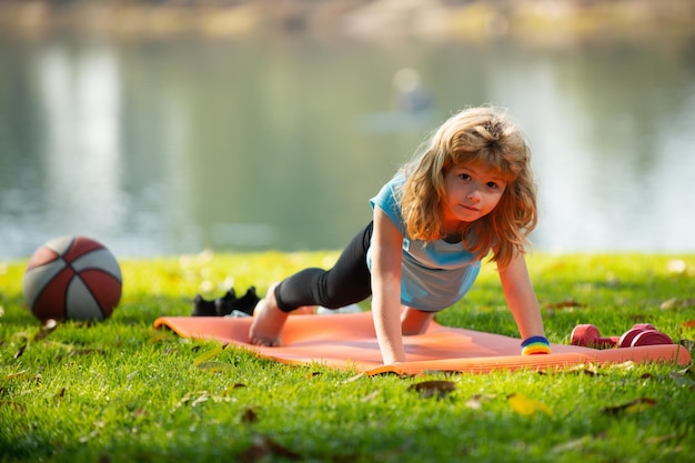 Il bambino sta facendo esercizi di push up nel parco primaverile attività sane bambini stile di vita forte bambino ex