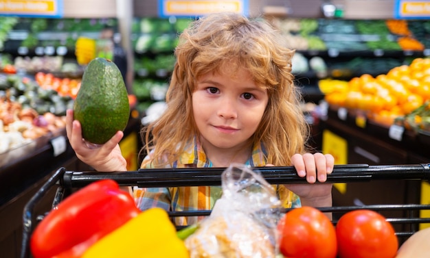 Il bambino sta facendo la spesa in un supermercato Cibo sano per una giovane famiglia con bambini Ritratto di bambino sorridente con carrello pieno di verdure fresche Bambini al supermercato o al supermercato