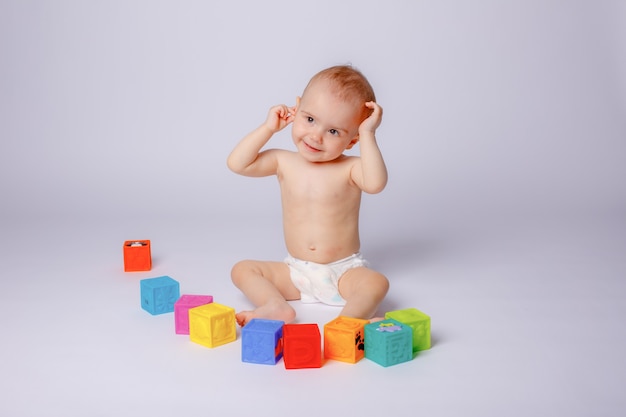 Il bambino sta giocando con cubetti colorati in un pannolino su sfondo bianco