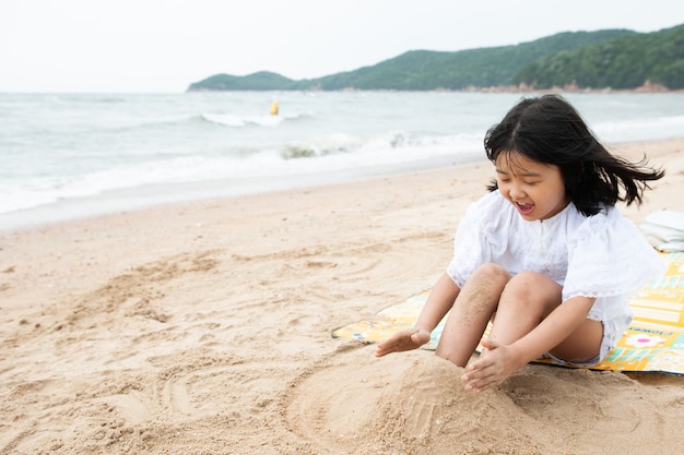 Il bambino sta giocando con la sabbia sulla spiaggia.