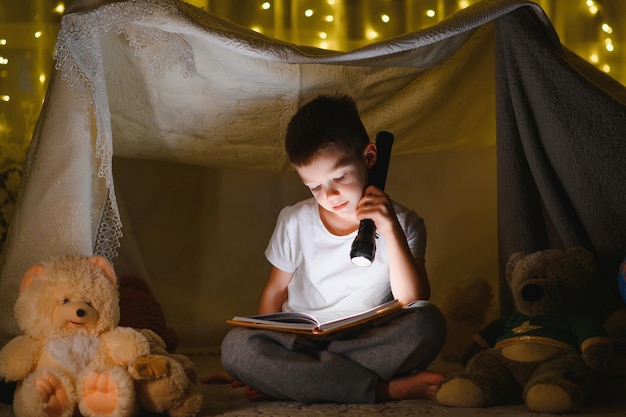 Il bambino sta leggendo un libro con una torcia