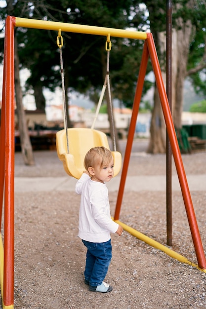 Il bambino sta nel parco giochi vicino all'altalena