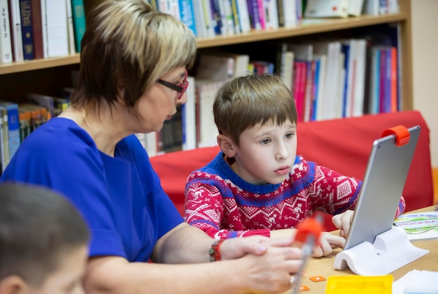 Il bambino sta studiando con l'insegnante al computer Lo studente della scuola primaria studia al tablet