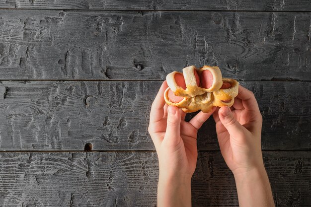 Il bambino sta tenendo una salsiccia fatta in casa in una pasta su legno nero