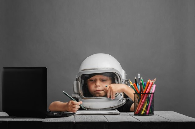 Il bambino studia a distanza a scuola indossando un casco da astronauta per tornare a scuola