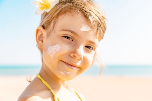 il bambino sulla spiaggia spalma la crema solare. Messa a fuoco selettiva