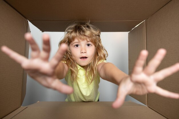 Il bambino sveglio allegro che apre una vista presente dall'interno della scatola prende dalla scatola aperta del regalo delle mani dei bambini a