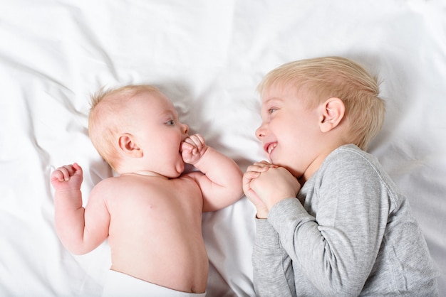 Il bambino sveglio e il fratello maggiore sorridente stanno trovandosi sul letto