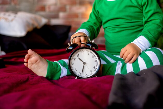 Il bambino sveglio in pigiama si siede vicino all'albero di Natale