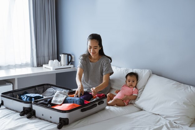 Il bambino sveglio si siede accanto alla madre che prepara i vestiti