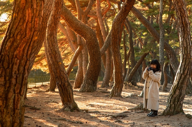 Il bambino tiene in mano una telecamera tra gli alberi.