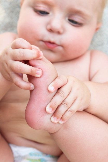 il bambino tiene la gamba e la guarda