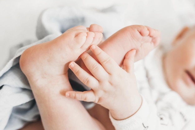 Il bambino tiene le gambe con la mano e si sdraia sul letto con una coperta gioca in posizione fetale da vicino