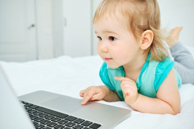 Il bambino usa il laptop sdraiato sul letto