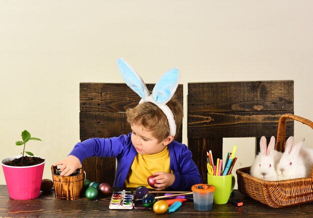 Il bambino va a caccia di uova di Pasqua. Acquista online per la decorazione di buona Pasqua.