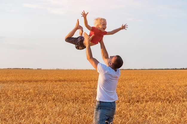 Il bambino vola tra le braccia del padre Papà lancia il figlio in aria Padre e figlio che giocano all'aperto