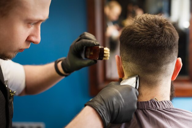 Il barbiere fa il taglio di capelli nel negozio di barbiere, primo piano della testa del cliente. Parrucchiere alla moda nel salone di capelli maschile