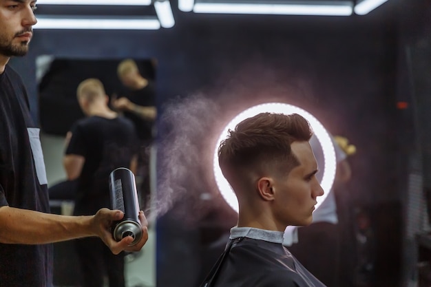 Il barbiere fa lo styling dei capelli con una lacca dopo il taglio di capelli presso il barbiere.