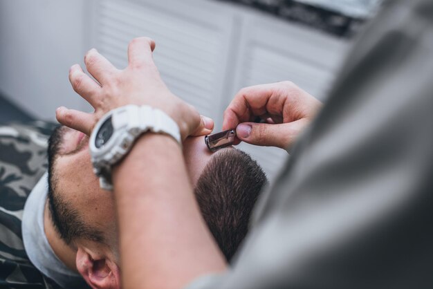 Il barbiere fa un'acconciatura ideale. Taglio di capelli sbiadito. Il parrucchiere esegue un rasoio pericoloso.